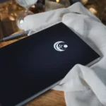 Couverture rigide noire du Journal de Rêves avec logo croissant de lune, plante et étoiles en blanc, posée sur table en bois avec ambiance cosy